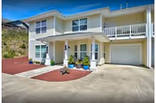 Front exterior of a two-story residential building with a covered entry, garage, driveway, and potted plants.