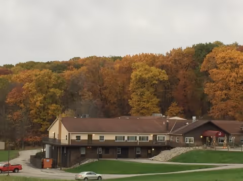 Exterior view of a senior living facility with autumn trees behind