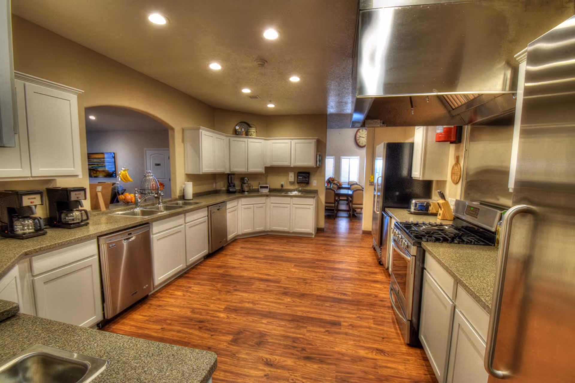 Spacious communal kitchen with white cabinets, stainless steel appliances, and wood-look flooring.