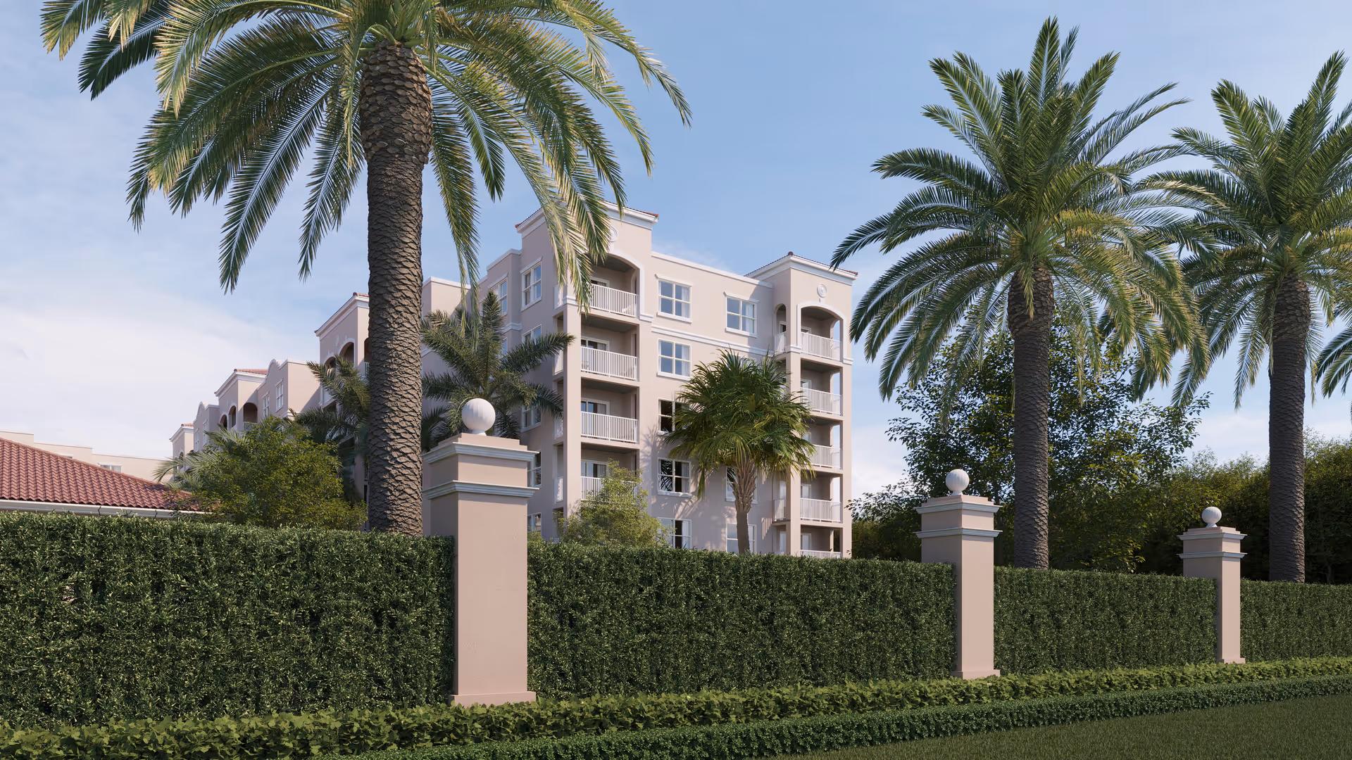 Multi-story light-colored assisted living building seen behind a manicured hedge and tall palm trees under a blue sky.