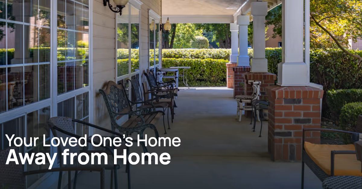 Covered outdoor porch with rows of chairs, brick columns and hedges, with text overlay reading "Your Loved One’s Home Away from Home".