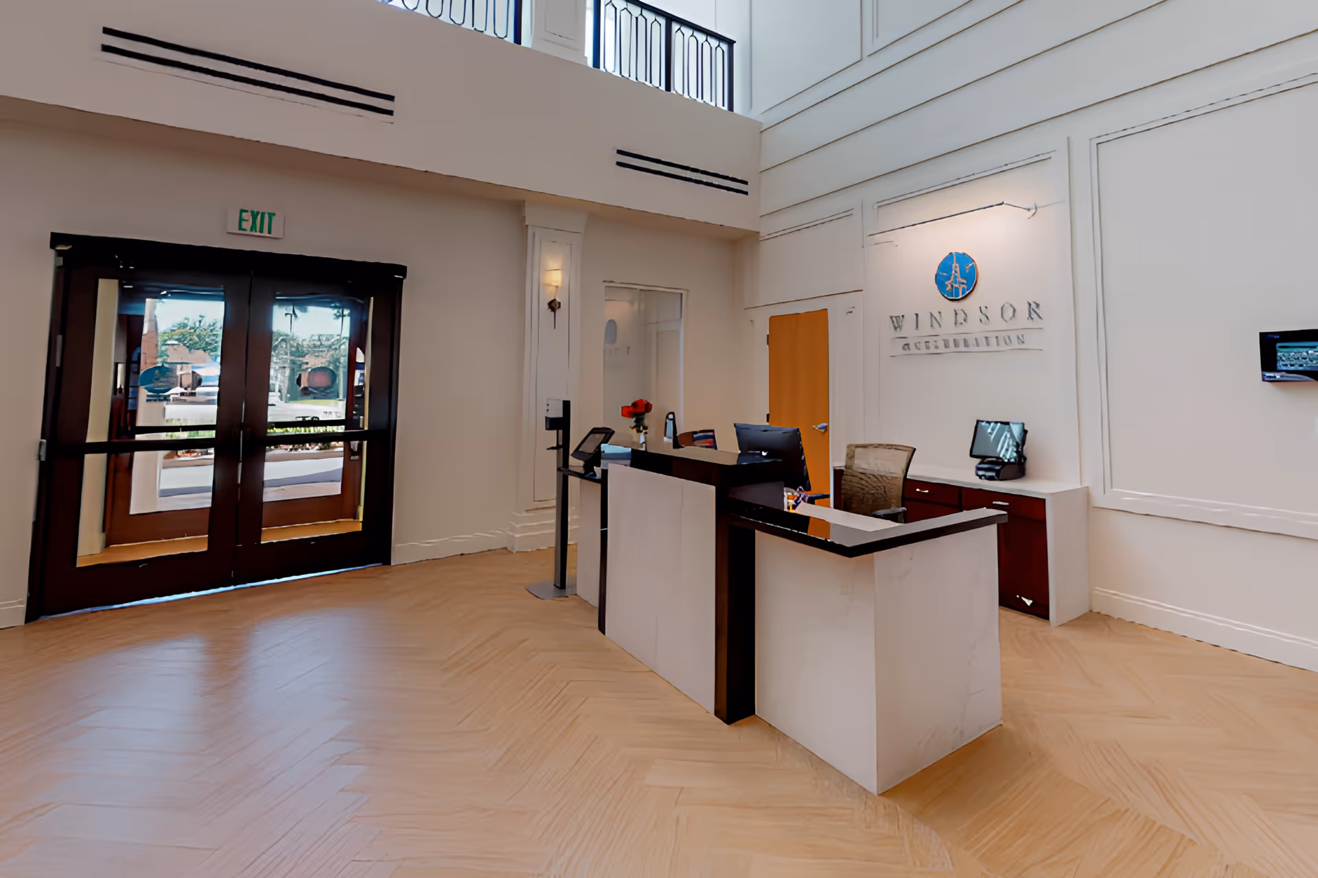 Lobby reception area with a front desk, double glass doors, and 'Windsor' signage on the wall.
