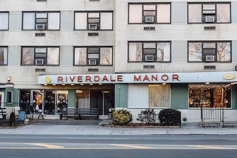 Riverdale Manor exterior building front with signage and storefront entrances along a sidewalk