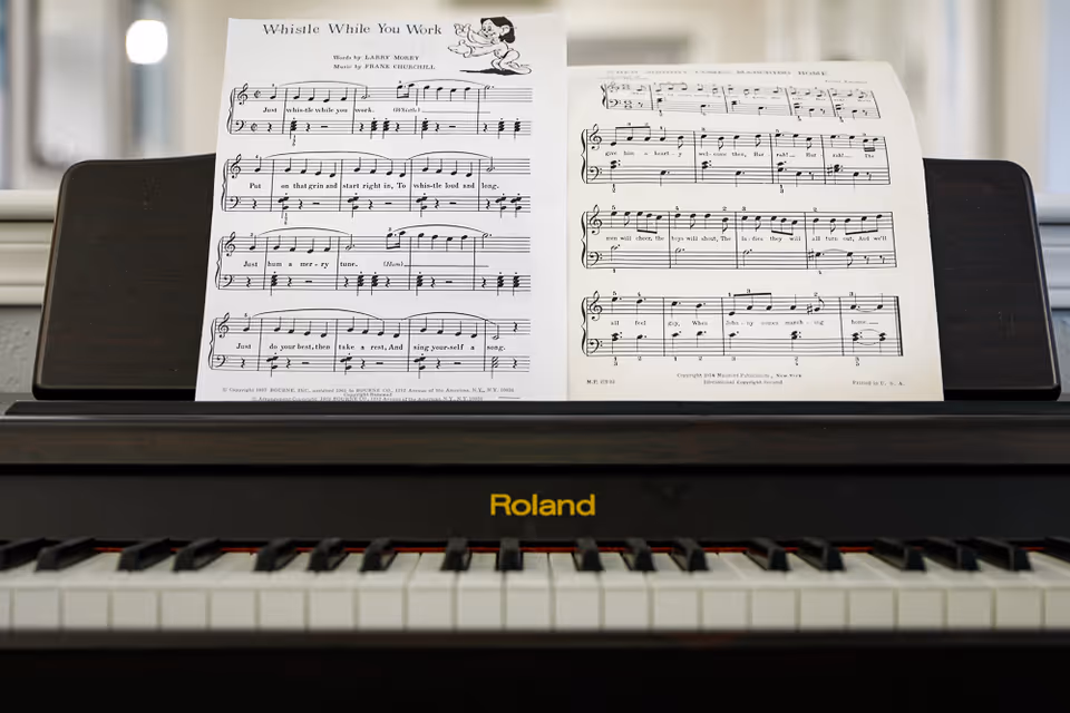 Close-up view of a Roland digital piano keyboard with sheet music titled 'Whistle While You Work' placed on the music stand.