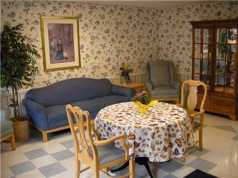 A floral-patterned living room with a round table, chairs, blue sofa, and glass cabinet.