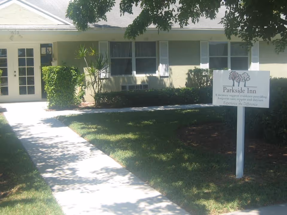 Front of Parkside Inn, a senior living facility with walkway and entrance sign.