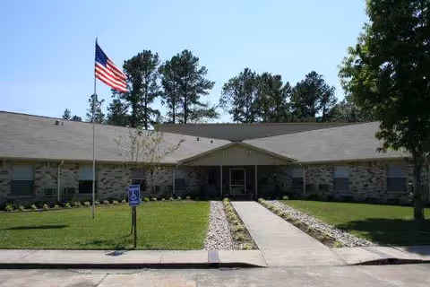 Hemphill Care Center exterior showing flag, lawn, and central walkway to entrance.
