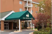 Brick senior living building entrance with a green canopy over the entry.