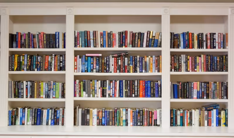 A white built-in bookshelf filled with a variety of books arranged neatly across multiple shelves.