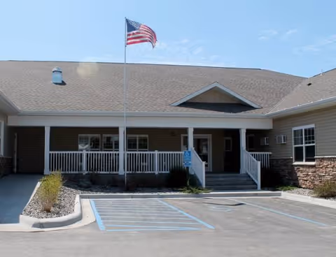 Front view of Cornerstone Residence of Fosston, showing entrance, wheelchair-accessible spaces, and flagpole.