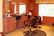Interior salon area with two styling chairs, mirrors, and shampoo basins in a warm-toned room.