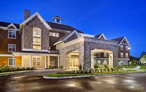Exterior view of Maplewood Senior Living facility with stone facade and covered entrance.