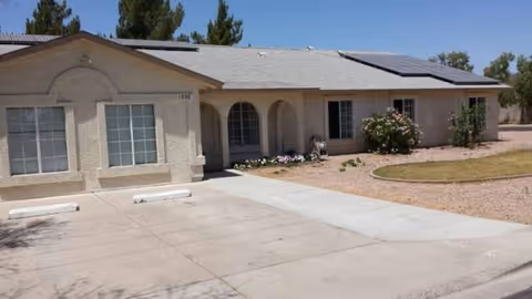 Single-story senior living facility front view with arched entry, windows, and desert landscaping.
