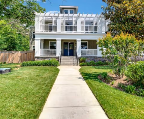 Two-story white senior living home with blue doors, front walkway, and green lawn.