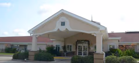 Front view of Brookdale Alexandria entrance with a covered drop-off and landscaping.
