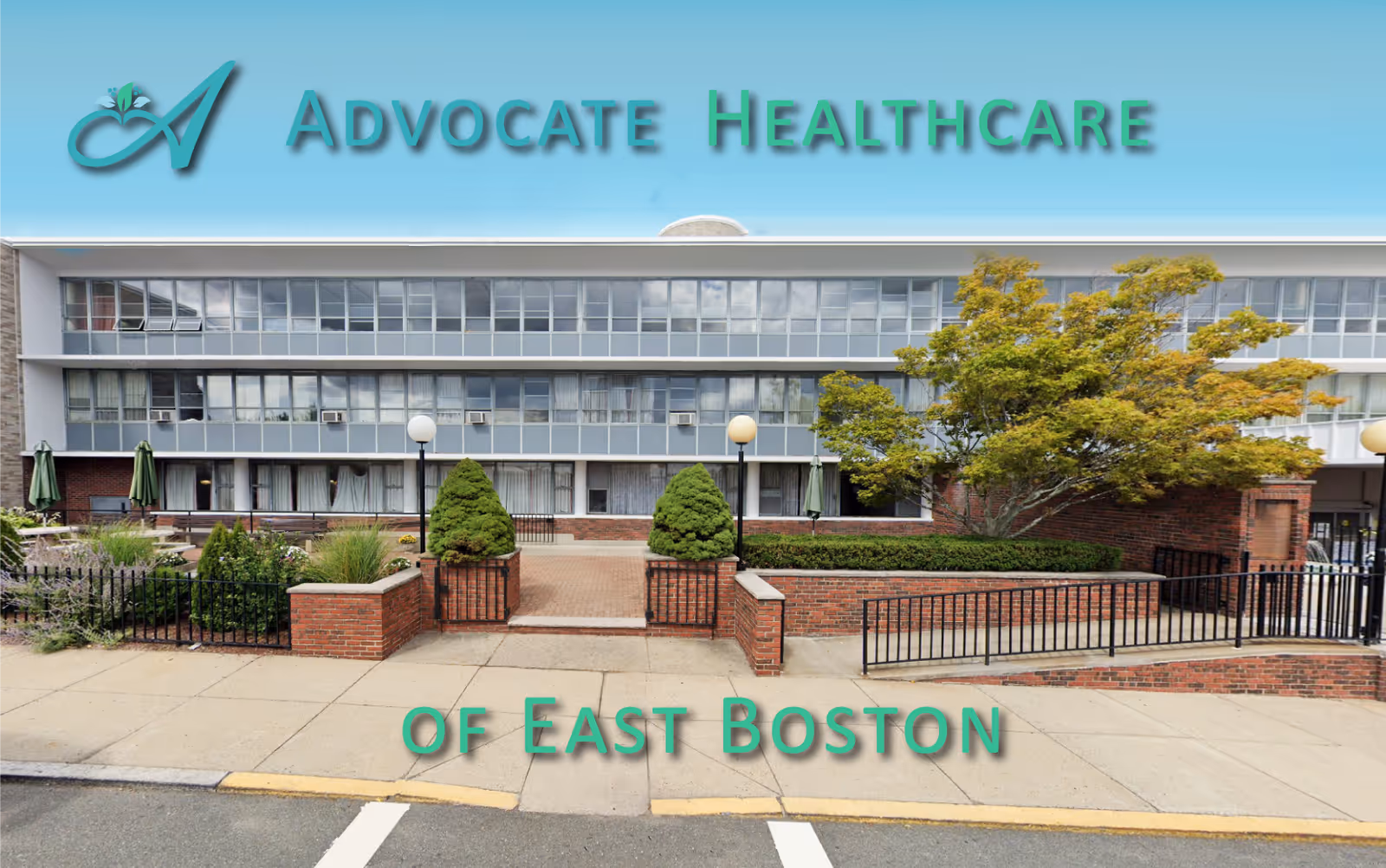 Exterior view of Advocate Healthcare of East Boston building with a brick entrance, greenery, and large windows under a blue sky.