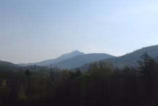 Distant mountain peaks and forested hills under a pale blue sky.