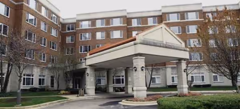 Brick senior living building with a covered entrance and pillars at the front