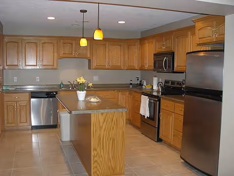 Bright kitchen with wooden cabinets, island, and stainless steel appliances.