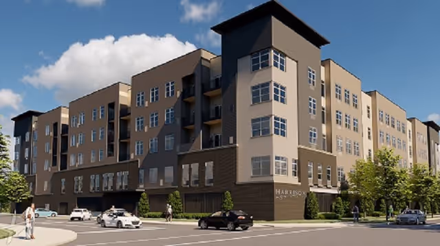 Front exterior view of a modern senior living building with parked cars and trees.