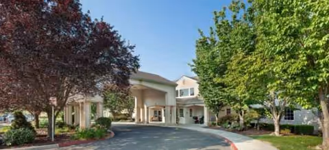 Front exterior entrance of Brookdale Walla Walla with driveway, trees, and landscaping.