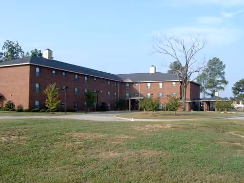 Exterior view of Rosa Parks Place, a brick senior living facility with lawn and trees.