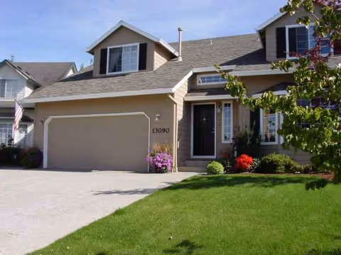 Front exterior of Blessing House senior living facility with garage, entryway, and landscaped yard.