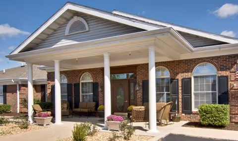 Bradford Court senior living facility exterior with brick facade, columns, and front porch seating.
