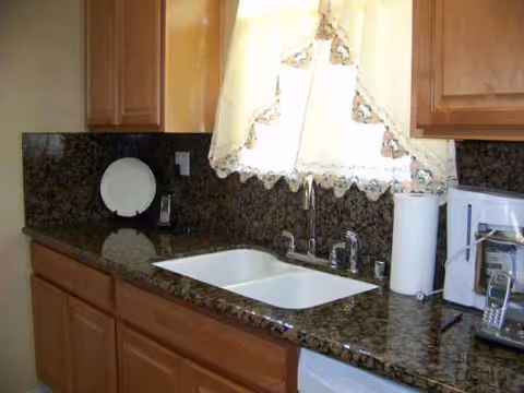 Kitchen area with granite counter, sink, cabinets, and small appliances.