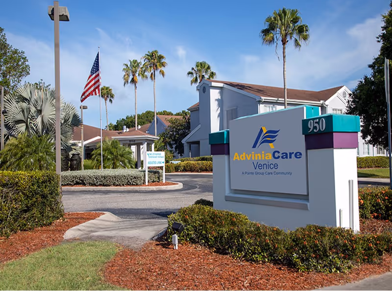 Front entrance and sign for AdviniaCare Venice with landscaped driveway, palm trees, and an American flag.