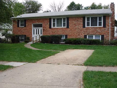 Brick senior living facility front exterior with walkway and manicured lawn