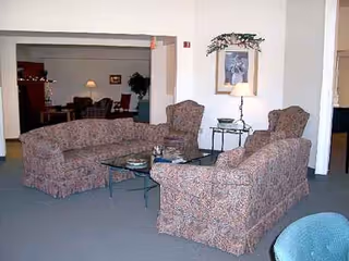 Indoor living room with patterned upholstered seating, coffee tables, and a wall lamp.