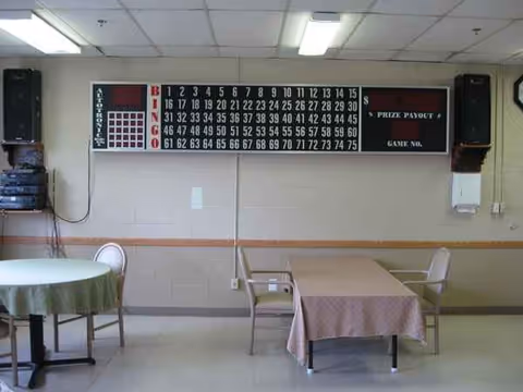 Recreation room with a large bingo board, tables, and chairs.