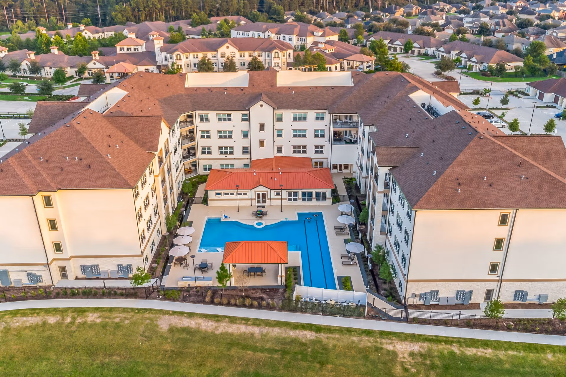 Aerial view of a multi-story senior living complex surrounding a central courtyard with a swimming pool and seating areas.