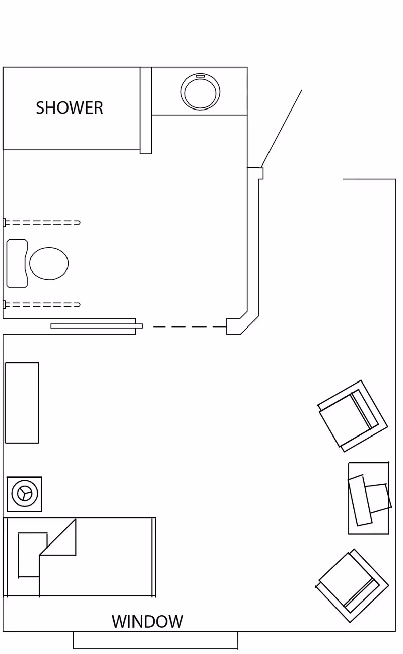 Floor plan of a small memory-care studio showing a bed, seating area, window, and an attached bathroom with shower, toilet, and sink.
