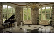 A spacious, elegant living room with large windows covered by patterned curtains, two beige sofas, a grand piano, and a chandelier hanging from the ceiling. The floor has a polished black and white checkered pattern.