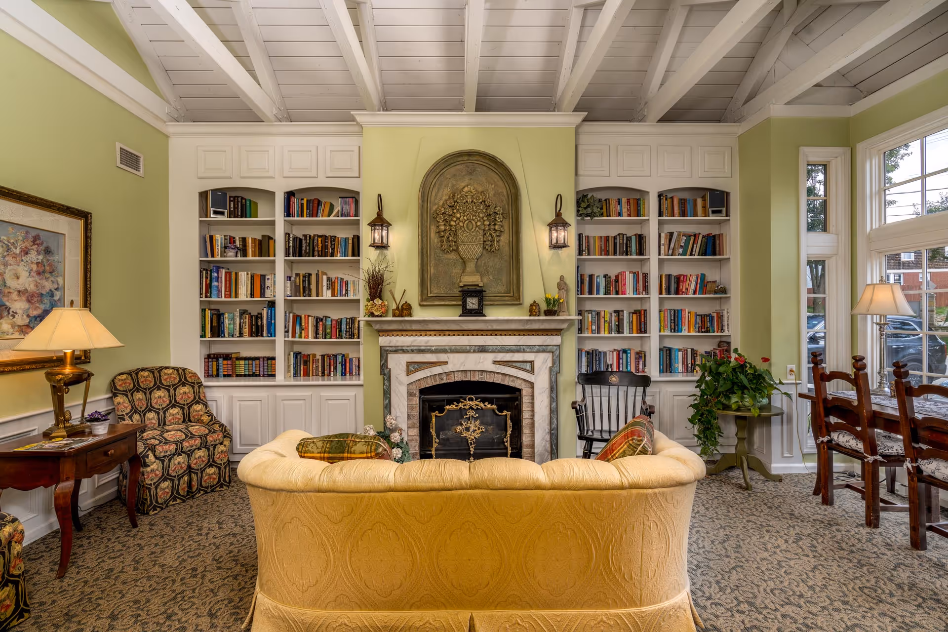 A cozy common living room with a yellow sofa facing a fireplace flanked by built-in bookshelves and additional seating.