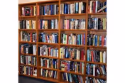 Wooden bookshelves filled with a variety of books in a well-organized library or reading area.