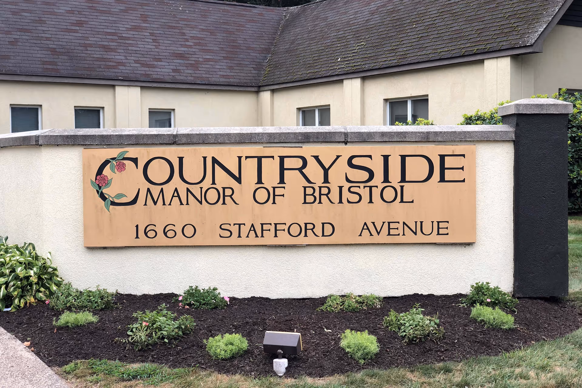 Exterior sign on a low wall reading "Countryside Manor of Bristol 1660 Stafford Avenue" in front of the facility building.
