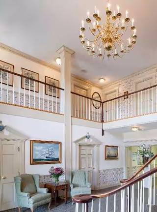 Elegant two story Birch Healthcare Center lobby with chandelier, balcony railing, and seating.