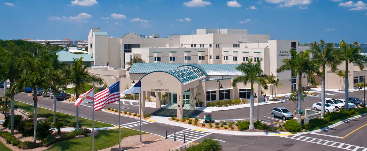 Aerial view of the Shell Point Retirement Community building, surrounded by palm trees and flags.