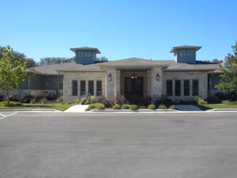 Front view of a single-story senior living facility with a stone façade and landscaped entrance.