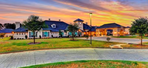 Exterior view of Arabella of Longview Senior Living at sunset with parking and landscaping.