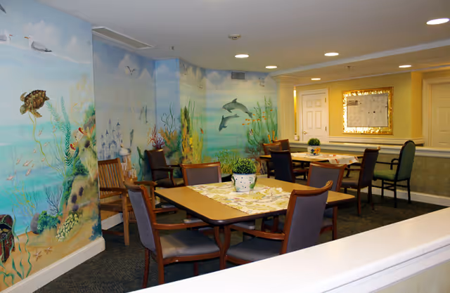Dining area with tables and chairs in a room featuring an underwater mural on the walls.