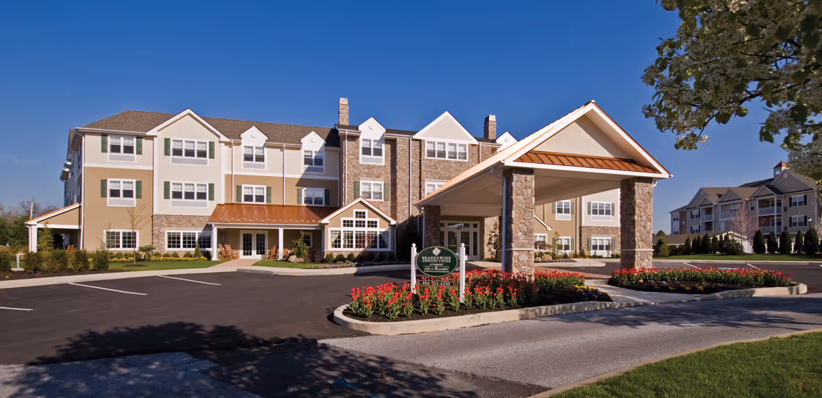 Exterior view of Brandywine Longwood by Monarch with sunlit entrance canopy and flower beds.