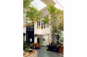 Interior view of a nursing center featuring a spacious common area with tall indoor trees, comfortable seating including armchairs, and large windows allowing natural light to brighten the space.