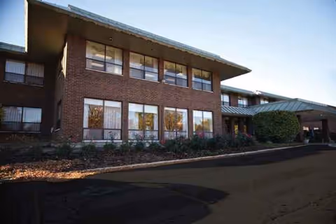 Two-story brick senior living facility with large windows and a covered entrance.