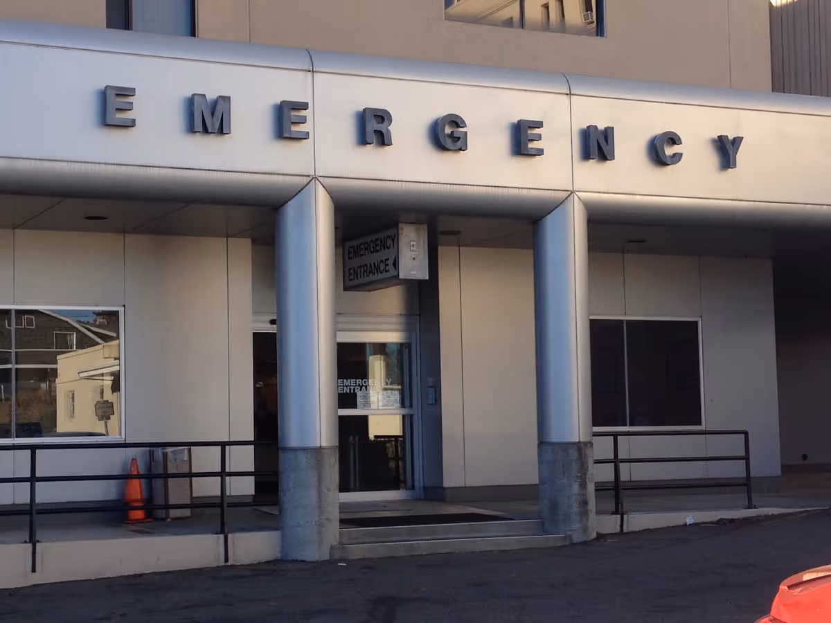 Entrance to a hospital emergency department with large 'EMERGENCY' letters above the doorway.