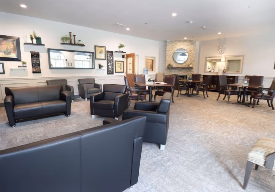 Spacious communal lounge with leather sofas, armchairs, and dining tables near a fireplace.