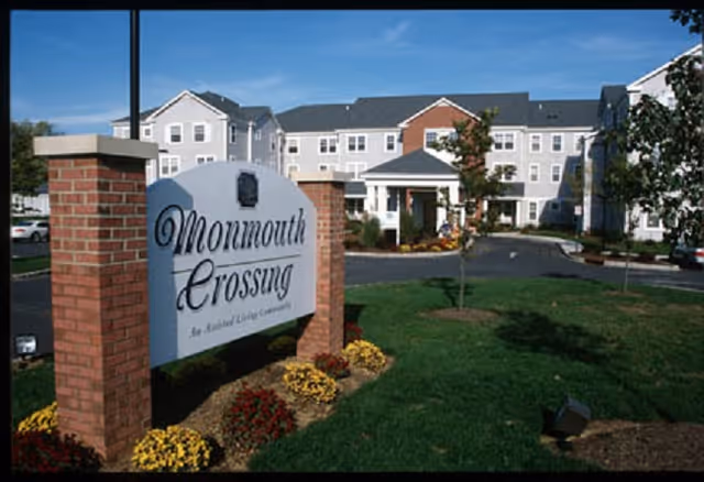 Exterior view of Monmouth Crossing senior living facility with sign and landscaping.